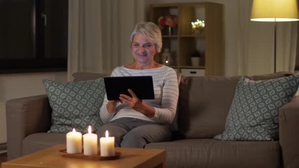 Mulher sênior feliz com tablet pc em casa à noite — Vídeo de Stock