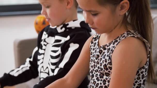 Дети в костюмах на Хэллоуин делают поделки дома — стоковое видео