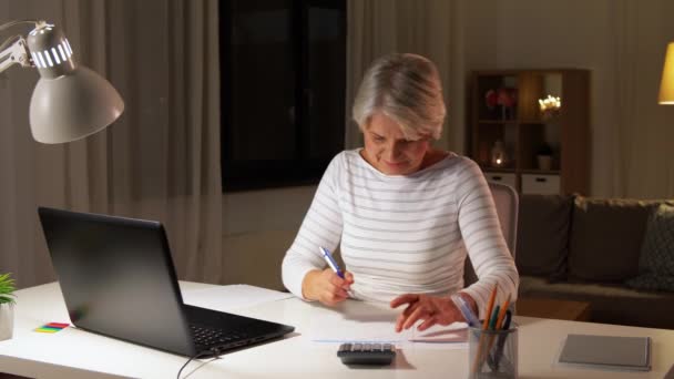 Seniorenvrouw vult 's avonds het belastingformulier in — Stockvideo