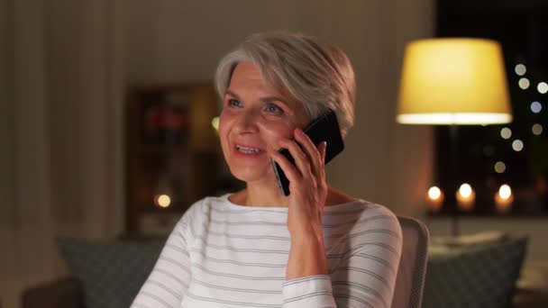 Пожилая женщина звонит на смартфон дома ночью — стоковое видео