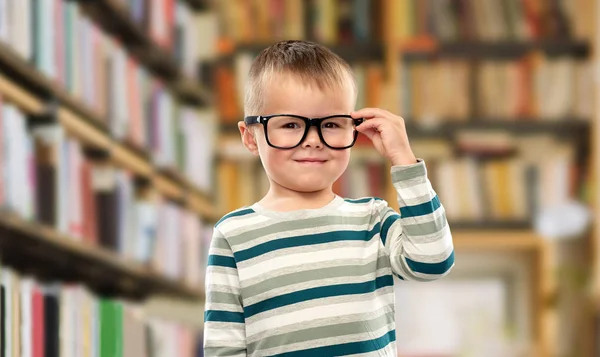 Портрет улыбающегося мальчика в очках над библиотекой — стоковое фото