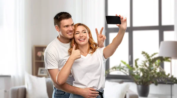 Feliz pareja en blanco camisetas tomando selfie —  Fotos de Stock