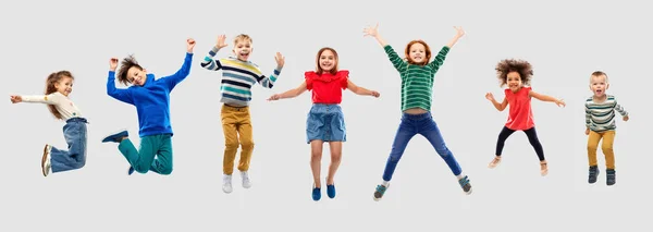 Niños felices saltando en el aire sobre fondo gris —  Fotos de Stock