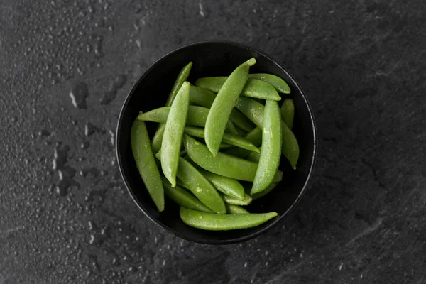 Petits pois dans un bol sur fond de pierre d'ardoise humide — Photo