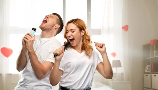 Glückliches Paar singt zu Haarbürste und Lotion — Stockfoto