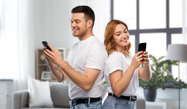 Casal feliz em camisetas brancas com smartphones — Fotografia de Stock