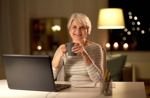 Seniorin mit Laptop trinkt zu Hause Kaffee — Stockfoto