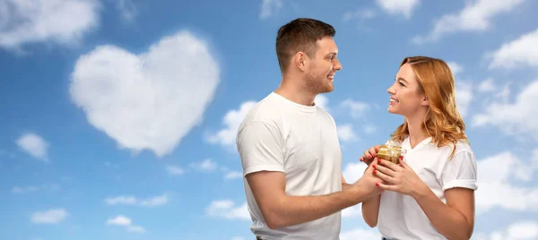 Happy couple in white t-shirts with gift — Stock Photo, Image