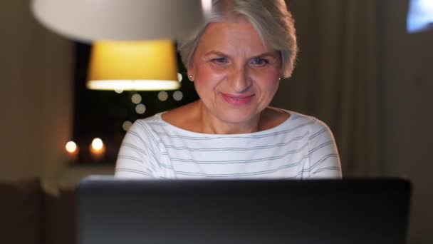 Szczęśliwa seniorka z laptopem w domu wieczorem — Wideo stockowe