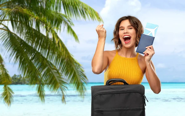 Gelukkige vrouw met ticket en reistas op het strand — Stockfoto