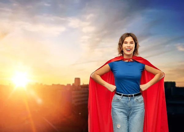 Mujer feliz en capa de superhéroe rojo sobre la puesta de sol de la ciudad —  Fotos de Stock