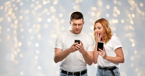 Cuplu fericit în tricouri albe cu smartphone-uri — Fotografie, imagine de stoc