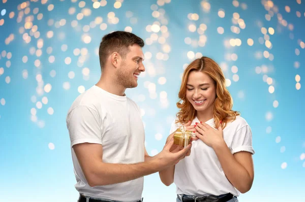 Szczęśliwa para w białych koszulkach z prezentem świątecznym — Zdjęcie stockowe