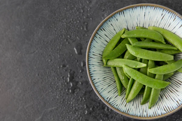 Petits pois dans un bol sur fond de pierre d'ardoise humide — Photo