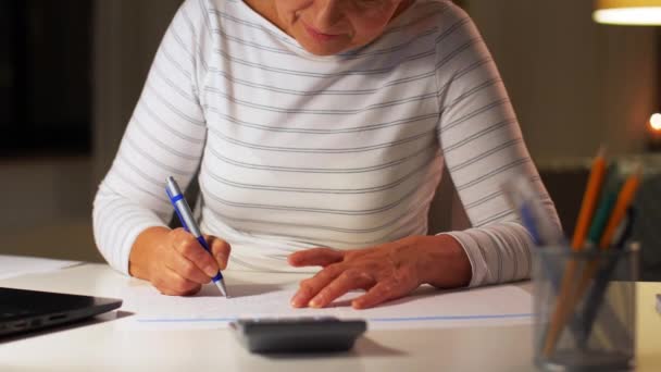 Mujer mayor llenando formulario de impuestos en casa por la noche — Vídeo de stock