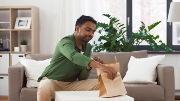 Hombre indio sonriente desempacando comida para llevar en casa — Vídeos de Stock