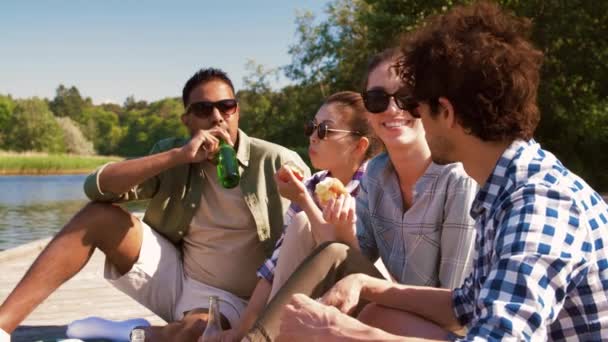 Друзі, які мають пікнік на пірсі на озері або річці — стокове відео