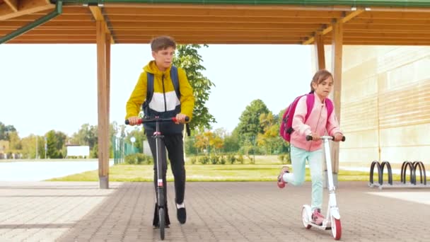 Barn ridning skotrar på skolgården — Stockvideo