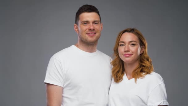 Pareja en camisetas blancas sobre fondo gris — Vídeos de Stock