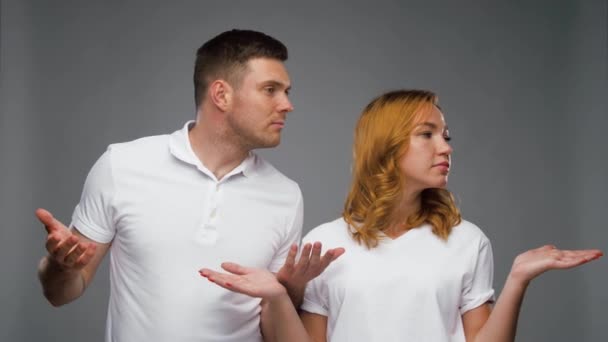 Pareja confusa en camisetas blancas encogiéndose de hombros — Vídeo de stock