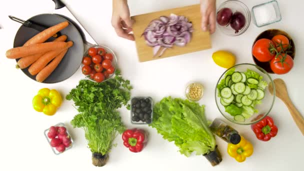 Молода жінка додає червону цибулю до салату вдома — стокове відео