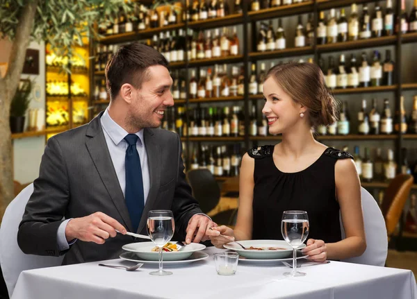 Uśmiechnięta para jedząca danie główne w restauracji — Zdjęcie stockowe