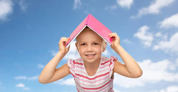 머리 위에 책으로 된 지붕 이 있는 어린 소녀 — 스톡 사진
