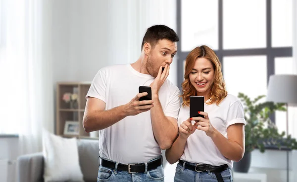 Casal feliz em camisetas brancas com smartphones — Fotografia de Stock