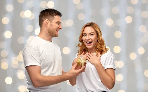 Glückliches Paar in weißen T-Shirts mit Weihnachtsgeschenk — Stockfoto