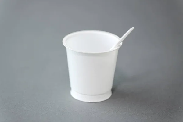 Белый одноразовый пластиковый стакан с ложкой — стоковое фото