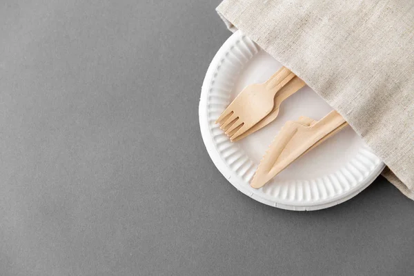 Widelce i noże drewniane na papierowych talerzach i serwetkach — Zdjęcie stockowe
