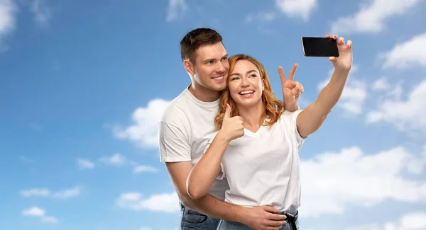 Feliz pareja en blanco camisetas tomando selfie —  Fotos de Stock