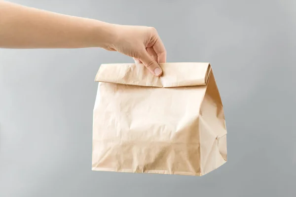 Hand hält Essen zum Mitnehmen in Papiertüte mit Mittagessen — Stockfoto