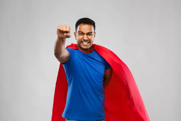 indian man in superhero cape flying over grey