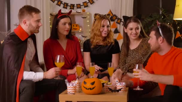 Счастливые друзья в костюмах Хэллоуина на домашней вечеринке — стоковое видео