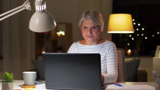 Пожилая женщина с ноутбуком пьет кофе дома — стоковое видео