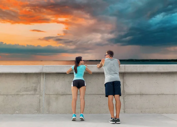 Feliz pareja haciendo ejercicio al aire libre en la pared de hormigón — Foto de Stock