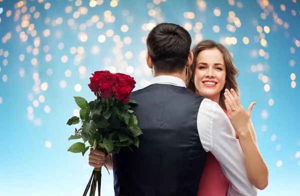 Woman with engagement ring and roses hugging man — Stock Photo, Image