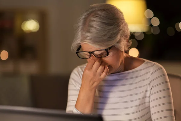 Mulher idosa cansada com laptop em casa à noite — Fotografia de Stock