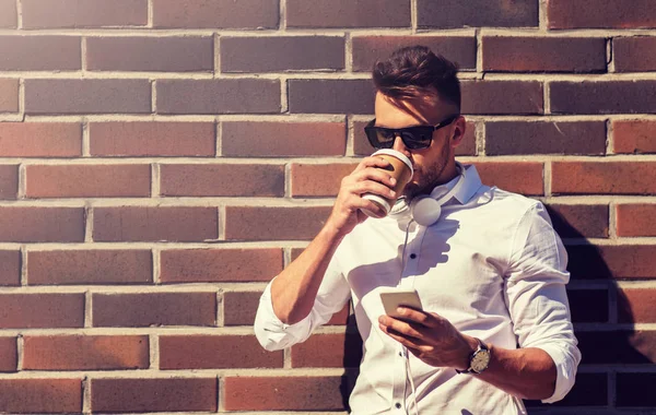 Hombre con teléfono inteligente y taza de café en la calle de la ciudad — Foto de Stock