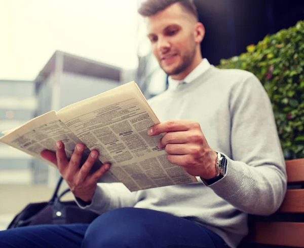 Hombre leyendo periódico en banco de la calle de la ciudad —  Fotos de Stock