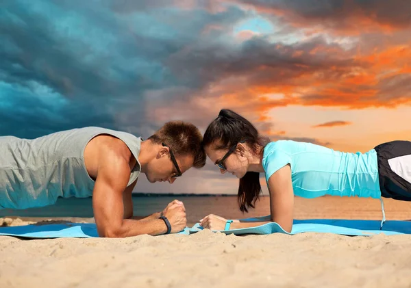 Pareja haciendo ejercicio de tablón en la playa de verano —  Fotos de Stock