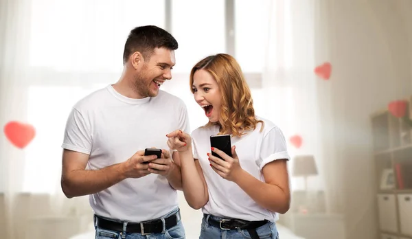 Happy couple in white t-shirts with smartphones — Stock Photo, Image