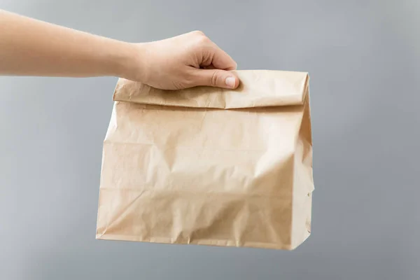 Mão segurando comida takeaway em saco de papel com almoço — Fotografia de Stock