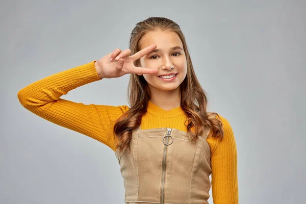 Uśmiechnięta młoda nastolatka dziewczyna pokazując pokój ręka znak — Zdjęcie stockowe