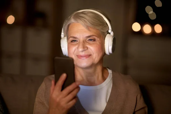 Старшая женщина в наушниках слушает музыку — стоковое фото