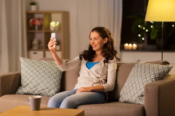Lycklig kvinna tar selfie med smartphone hemma — Stockfoto