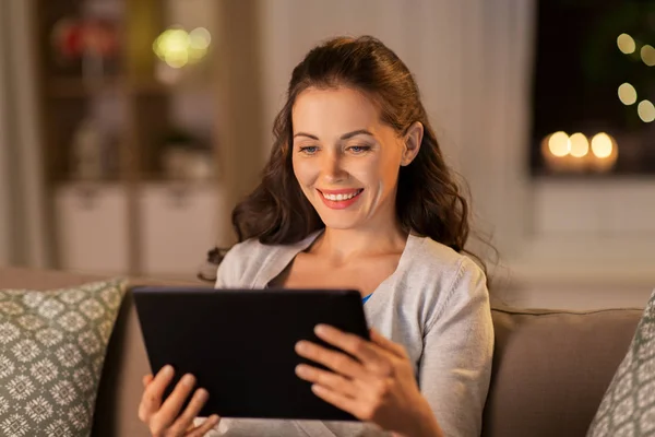 Glückliche Frau mit Tablet-PC abends zu Hause — Stockfoto