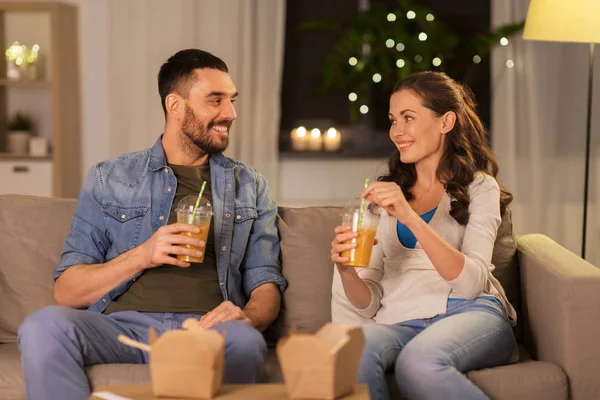 Feliz pareja bebiendo jugo para llevar en casa — Foto de Stock