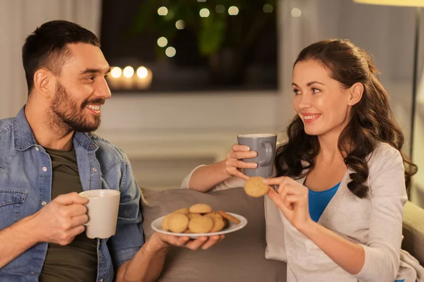 Feliz pareja bebiendo té con galletas en casa — Foto de Stock